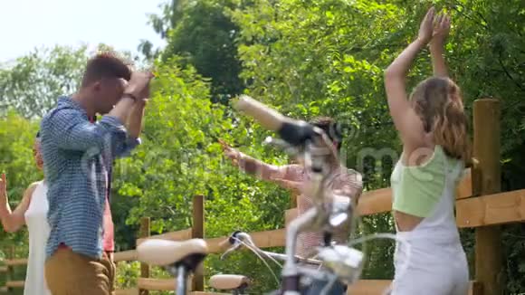 快乐的朋友骑自行车在夏日公园跳舞视频的预览图