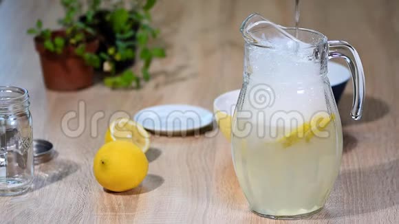 在一壶柠檬里倒水一杯苏打水喝柠檬水加冰和白柠檬片视频的预览图