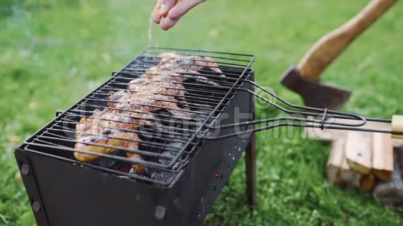 厨师在户外烤架的热煤上做烧烤并在鸡翅的脆皮上添加香料在视频的预览图
