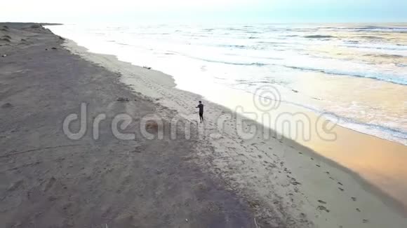 在日出时在海滩上慢跑的年轻有魅力的男人身上用无人机进行空中巡逻健身运动和健康运动视频的预览图