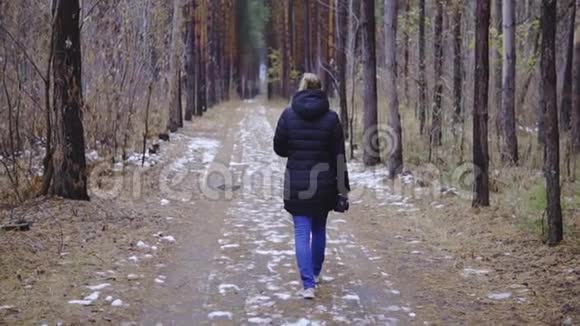 慢动作电影那个女孩正沿着森林里的路走第一场雪视频的预览图
