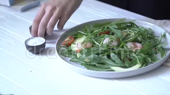 女性手调整酱汁和芦笋叶沙拉中的虾视频的预览图