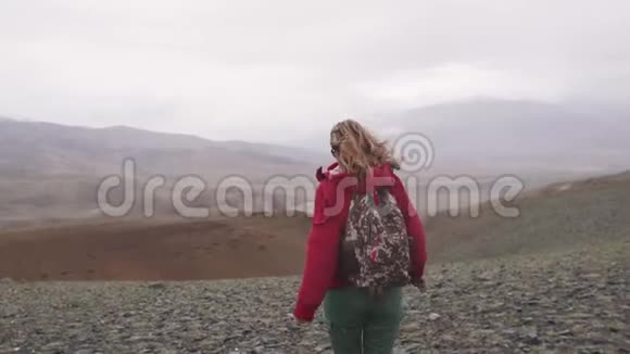游客在倾盆大雨中走过山旅行女孩带背包背面视图视频的预览图
