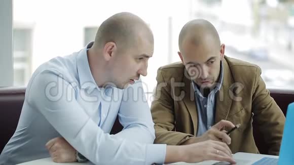 两个商人在办公室开会时用笔记本电脑视频的预览图