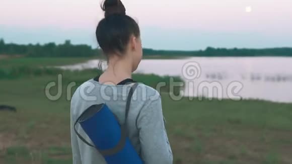 年轻女子走路做早操拿着蓝色瑜伽垫的女孩视频的预览图