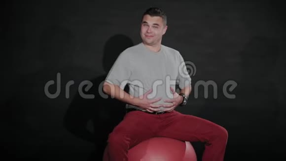 在体操球上肚子大的年轻人视频的预览图