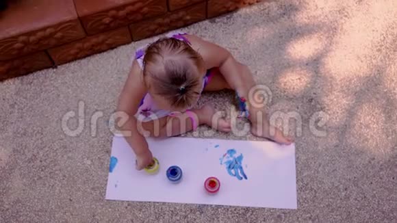 漂亮的小女孩用手指在一张白纸上画画在幼儿园或视频的预览图