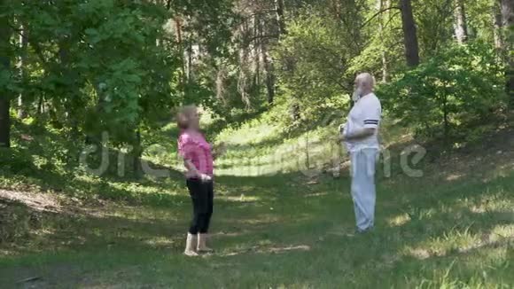 一位老人和一位老年妇女在夏季公园做体育锻炼视频的预览图