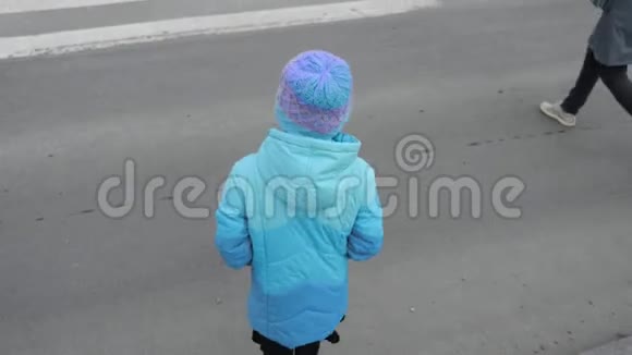 一个穿着蓝色夹克的年轻女孩穿过斑马穿过马路穿过城市视频的预览图