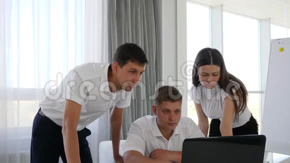 快乐的商业伙伴拍手坐在办公场所的笔记本电脑前视频的预览图