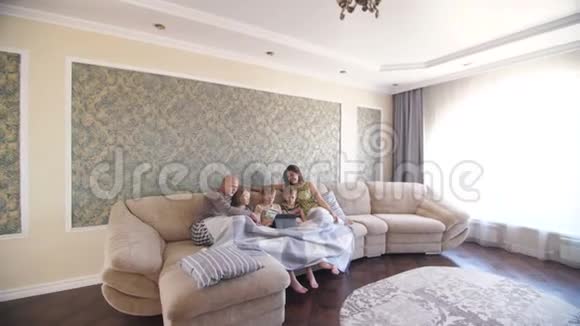 一家人坐在沙发上玩平板电脑视频的预览图