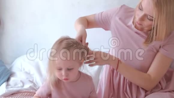 年轻迷人的金发母亲把头发扎成辫子她的小女儿穿着粉红色的连衣裙而她画的是视频的预览图