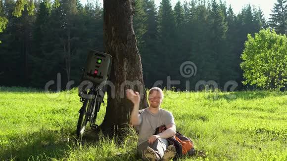 在阳光明媚的一天男子游客骑着自行车在夏天的森林里休息视频的预览图