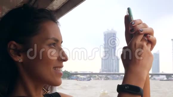 年轻的混血旅游妇女在泰国小船上巡游并使用手机拍照泰国曼谷4K视频的预览图