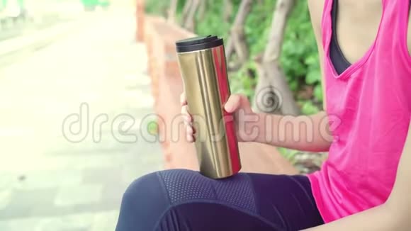 健康美丽的年轻亚洲跑步女子饮水因为在城市公园街头跑步后感到疲倦视频的预览图