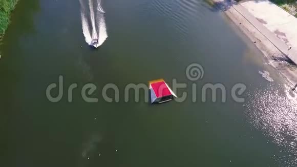 滑水的人在船后游泳跳在红色蹦床上的鸟瞰图视频的预览图