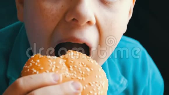 一个十几岁的男孩在近景的快餐店吃汉堡包吃汉堡的男孩的嘴视频的预览图