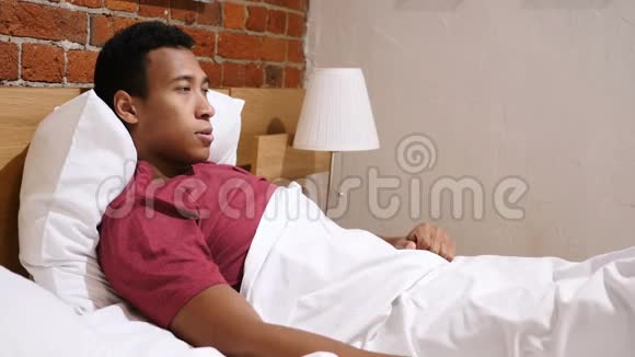 愤怒沮丧的非洲男人躺在床上疯狂视频的预览图
