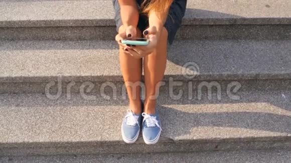 年轻混合种族学生女孩使用手机坐在老图书馆楼梯4K视频的预览图