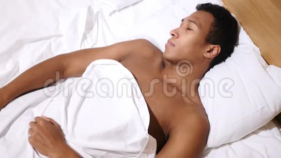 从早晨的睡眠中醒来的放松的非洲男人视频的预览图