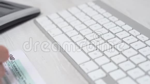 电脑键盘和计算器旁边桌子上的1040妇女填写税单的特写滑块运动4k视频视频的预览图