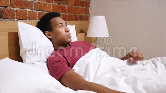累了的非洲男人脖子疼躺在床上休息视频的预览图