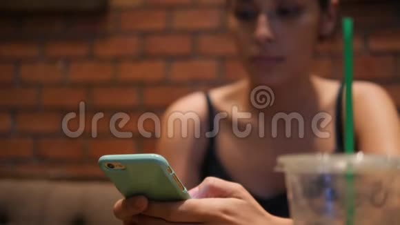 年轻迷人的混合种族女孩短信手机和喝抹茶绿茶在咖啡店4K泰国视频的预览图