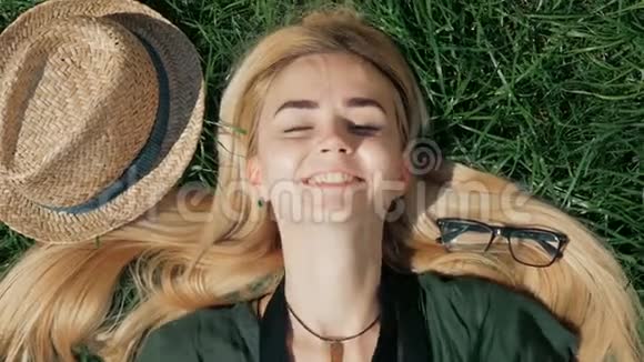 年轻的女游客躺在草地上度假时用复古相机拍照视频的预览图