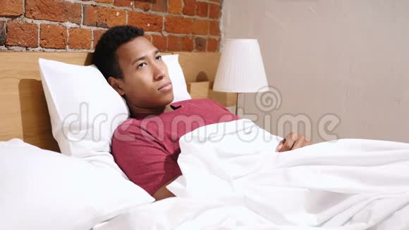 头痛紧张的非洲男人在床上放松视频的预览图