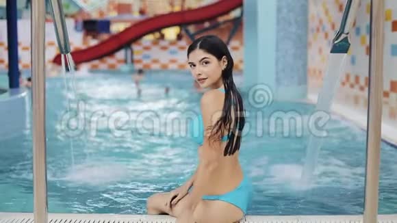 漂亮的女人坐在游泳池附近泳池边上那个被晒黑了的女孩视频的预览图