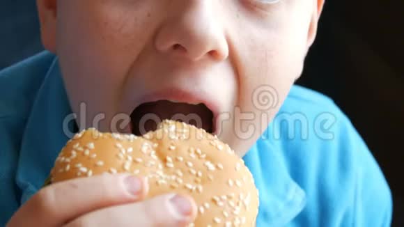 一个十几岁的男孩在近景的快餐店吃汉堡包吃汉堡的男孩的嘴视频的预览图