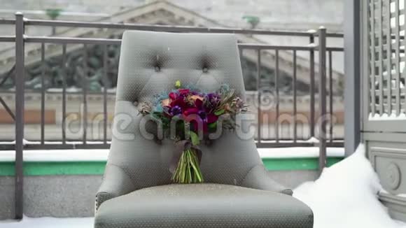 婚礼新娘花束在冬天雪天的露台上的椅子上视频的预览图