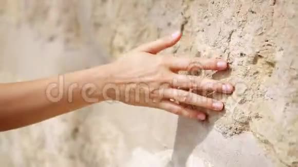 女人手移过旧石壁一直滑下去感性的触摸坚硬的石头表面视频的预览图
