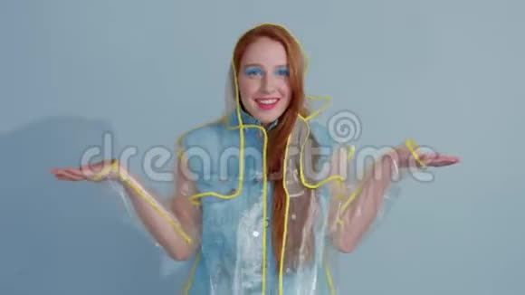 穿着透明雨衣流行艺术鲜艳彩妆跳舞的姜发女人视频的预览图