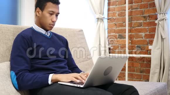 紧张和头痛的非洲男人在笔记本电脑上工作视频的预览图