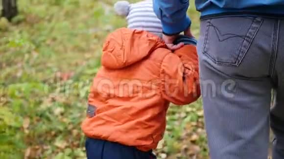 一位年轻的父亲和孩子一起在公园里散步父亲牵着儿子手温柔和拥抱她心爱的父亲视频的预览图