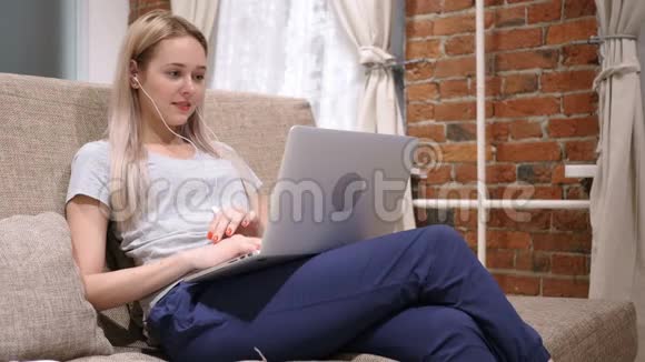 女人在笔记本电脑上享受听音乐在家放松视频的预览图