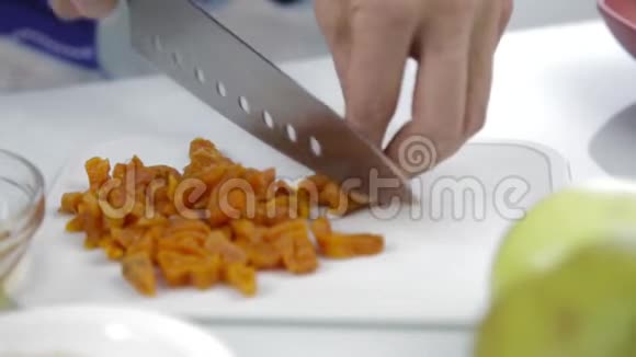 双手用大刀在砧板上切碎干燥的杏烹饪健康食品视频的预览图