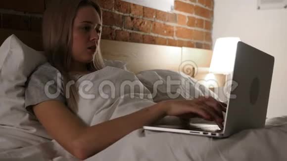 愤怒沮丧的女人在床上晚上在网上工作视频的预览图
