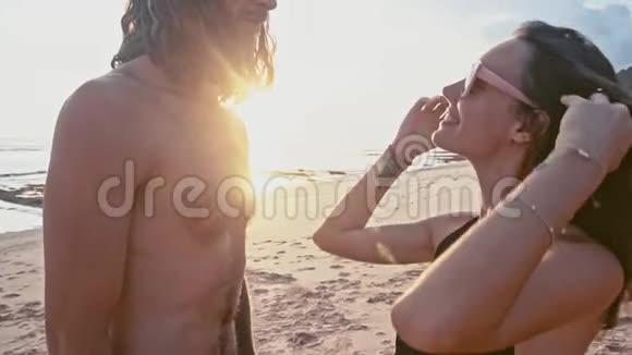 迷人的年轻旅行夫妇在海滩上享受日落接吻牵手塑造心形视频的预览图