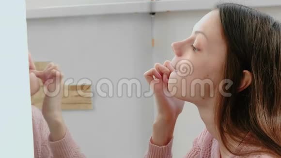 年轻女子在镜子前检查和看她的牙齿面的特写视频的预览图