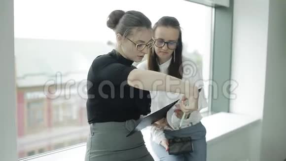 两位年轻的美女在窗户附近讨论不同的文件视频的预览图