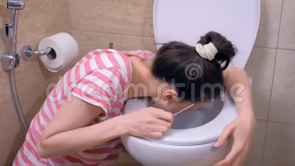 晨吐年轻的孕妇疲惫的女人在坐在家里地板上的厕所里呕吐视频的预览图