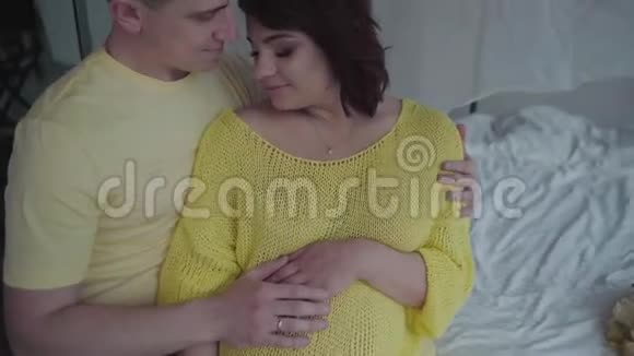 英俊的男人和他怀孕的妻子在家里聚在一起视频的预览图