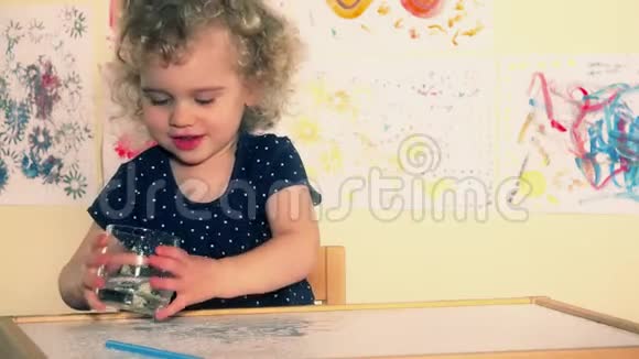 好奇的幼儿把水倒在桌子上兴奋的湿孩子在玩水视频的预览图