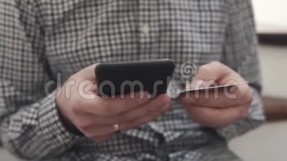 男人手里拿着智能手机和信用卡打字特写视频的预览图