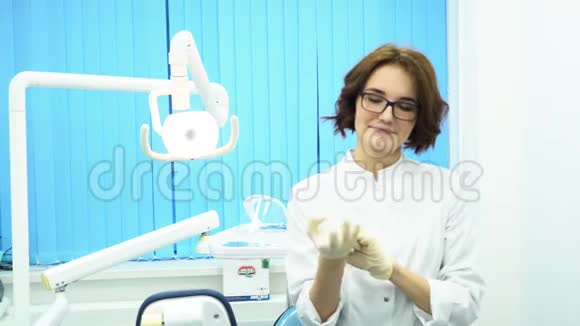 一位戴着医疗手套的漂亮年轻女医生的肖像戴手套戴眼镜的女牙医助手视频的预览图