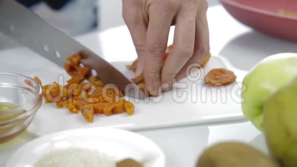 双手用大刀在砧板上切碎干燥的杏烹饪健康食品视频的预览图