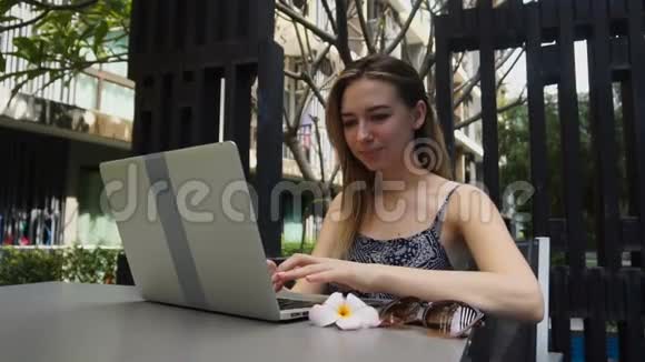 年轻女孩在度假时用笔记本电脑和男朋友说话慢动作视频的预览图