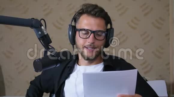 录音室关闭戴眼镜的年轻人在收音机工作时把文字读成麦克风视频的预览图